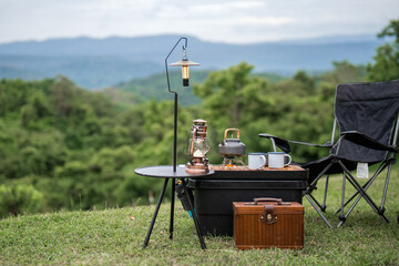 A table with a lantern and a tea kettle on it, and a black chair next to it. The scene is set in a...