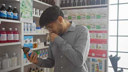 Bearded man examining medication in a pharmacy while coughing