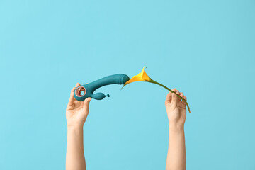 Female hands with vibrator and calla lily on color background