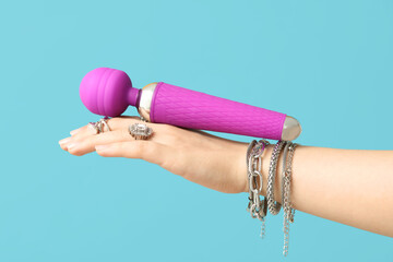 Female hand with stylish accessories and vibrator on color background, closeup