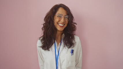 Smiling middle-aged hispanic woman with glasses and lab coat isolated against a pink background