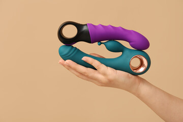 Woman holding vibrators on color background, closeup