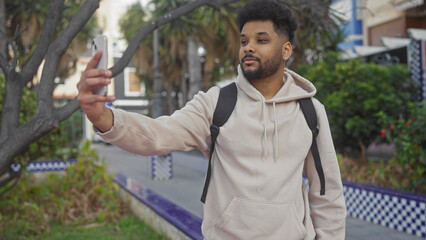 Handsome black man taking selfie with smartphone outdoor in city park.