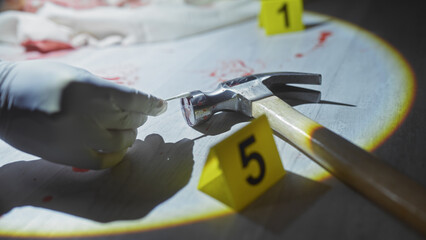 Close-up of gloved hand examining bloody hammer at crime scene with evidence markers