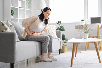 Young woman suffering from severe abdominal pain at home