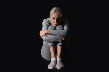 Mature woman having panic attack on black background