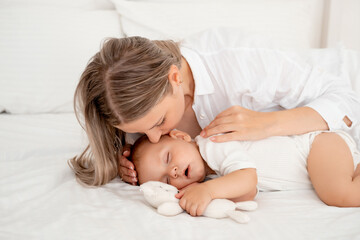 mom puts the baby to sleep hugging and kissing him before going to bed, healthy sleep together with...