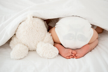 the baby's legs are in focus, the newborn baby sleeps sweetly on his tummy, a place for text, the...