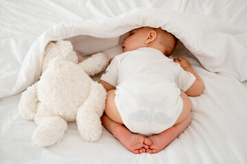 the baby's legs are in focus, the newborn baby sleeps sweetly on his tummy, a place for text, the...