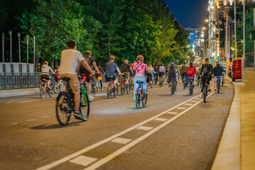 Fototapeta premium People cycling together at night along city street
