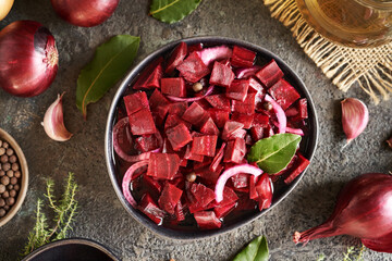 Fermented red beet kvass in a dark bowl with onions, garlic, bay leaf and spices