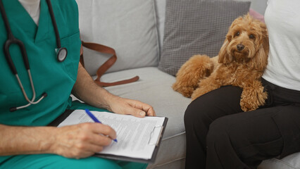 In a cozy home setting, a man in medical attire sits with a clipboard beside an attentive poodle on...