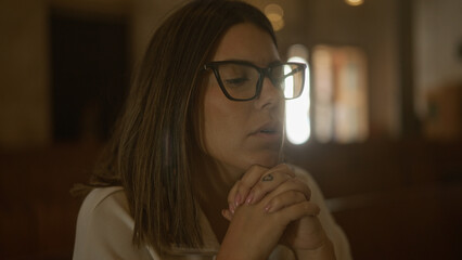 Young hispanic woman praying inside a church in italy, showcasing her faith and spirituality in a serene setting.