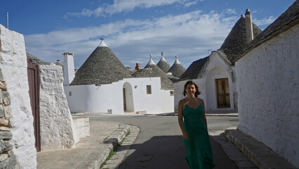 A beautiful young hispanic woman in a green dress walks down a street in the historic old town of...