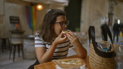 A young hispanic woman enjoys pizza at a restaurant terrace in italy, highlighting her beautiful look and the casual dining atmosphere.