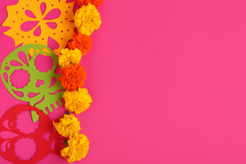Composition with beautiful marigold flowers and paper decor on color background. El Dia de Muertos
