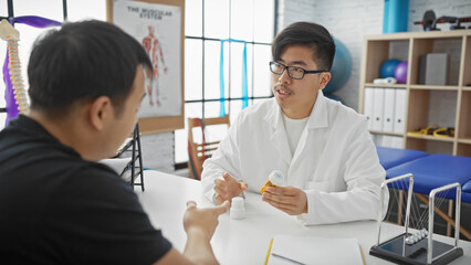 Obraz premium A male doctor consults with a male patient in a clinic discussing medication while holding a pill bottle.