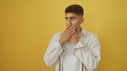 Young arabian man in thoughtful pose wearing white shirt against a yellow background isolated cutout