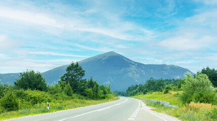 Naklejka premium Scenic road leading towards a lush, mystic Rtanj mountain, under a clear blue sky. Serbia.