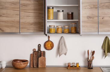 Glass jars with different products on shelves in kitchen