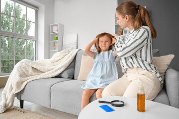 Obraz premium Mother checking her little daughter's head with pediculosis at home