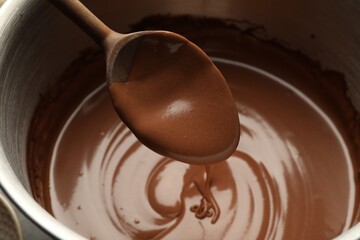 Chocolate dough dripping from spoon into bowl, closeup