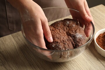Woman kneading chocolate dough at wooden table, closeup