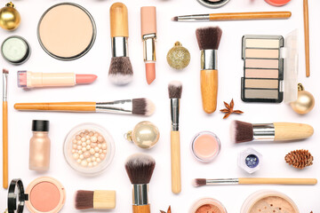Different makeup brushes, decorative cosmetics and Christmas decor on white background, flat lay