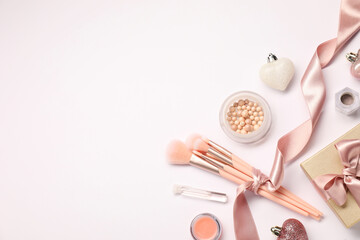 Different makeup brushes, decorative cosmetics and Christmas decor on white background, flat lay. Space for text