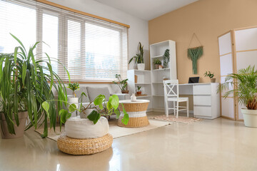 Interior of living room with green houseplants, sofa and tables