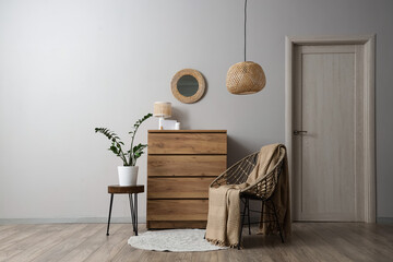 Interior of light living room with mirror, commode and armchair