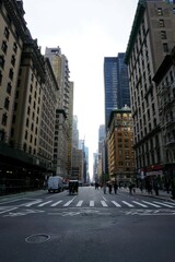 Geschäftiges Leben zwischen Wolkenkratzern und historischer Architektur auf den Straßen von New York City; Häuserflucht 57 Street, Manhattan, mit Menschen und Autos