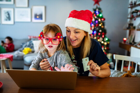 Mom and kid doing Christmas online shopping with laptop and credit card
