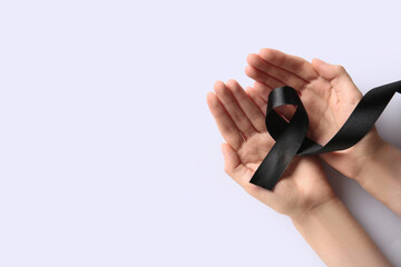 Female hands with black ribbon on white background. World Cancer Day
