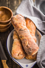 Crusty rustic baguette in bowl on wooden table.
