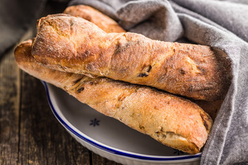 Crusty rustic baguette in bowl on wooden table.