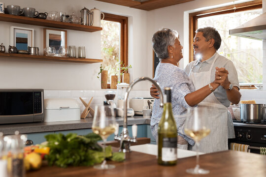 Dance, love and mature couple in kitchen for bonding, loving relationship and romance together in home. Retirement, marriage and happy man and woman with wine for cooking meal, lunch and dinner