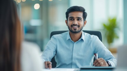 An HR manager from India provides professional advice to team members at a desk, fostering collaboration and effective communication in a modern office environment