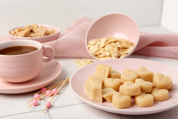 Plate with tasty marzipan candies, almond flakes and cup of coffee on light tile table