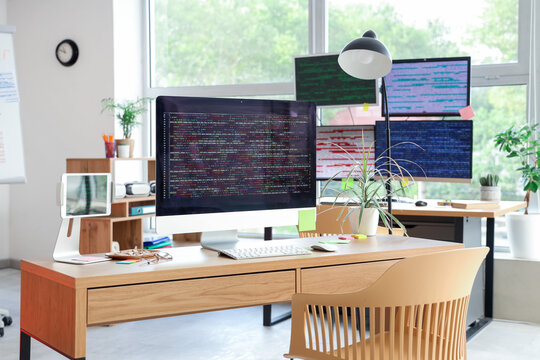 Computer monitor with code and plant on programmer's desk in light office