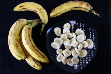 Banany i plasterki bananów na czarnym tle © Monika