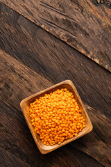 Lens culinaris - Organic unshelled red lentil in square bowl.