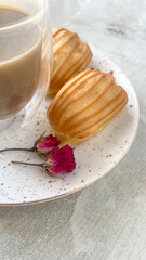 A cup of coffee and eclairs, a plate of profiteroles on a light gray marble background, a delicious breakfast.