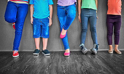 Fashion, row and legs of children on wall background for trendy outfit, causal clothes and style. Diversity, youth and shoes of boys and girls in studio for back to school, education and learning