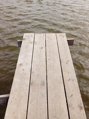 Fototapeta premium Vertical photo of a wooden old pier above the surface of a lake.