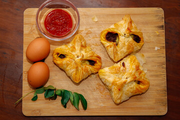 Kerala Style Tasty Egg Puffs with Tomato Sauce, Curry Leaves and Egg On Chopping Board