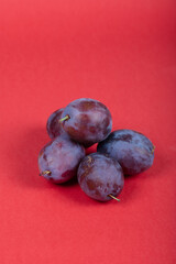 Fresh Purple Plums on Red Background – Isolated Juicy Fruits Perfect for Healthy Eating and Food Photography