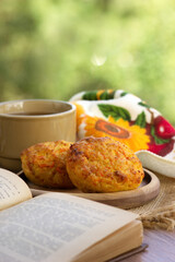 Breakfast on the windowsill against the backdrop of nature. Tea, cheesecakes, a book symbolize coziness. Morning and breakfast.