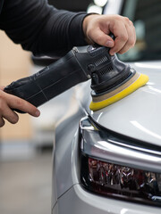 Process of polishing white car hood surface using orbital polishing machine. . Vertical photo. 
