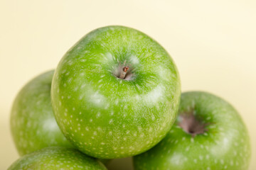 Fresh Green Apples: Trio of Crisp Granny Smith Fruits on Pale Yellow Background - Healthy Snack, Organic Produce, and Natural Vitality in Minimalist Setting
